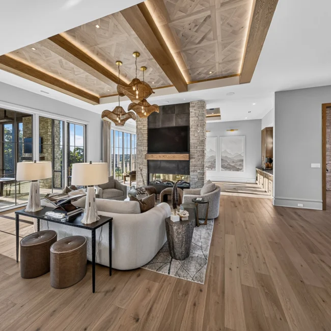 Sunset Heights great room with a beamed wood ceiling, stone fireplace, cream sofas and sliding glass doors to the covered porch