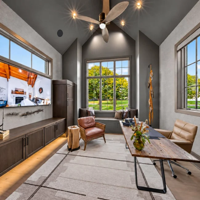 Sunset Heights home office with a dark vaulted ceiling, wood built-in TV cabinet, live-edge desk, leather chairs and windows facing the lawn