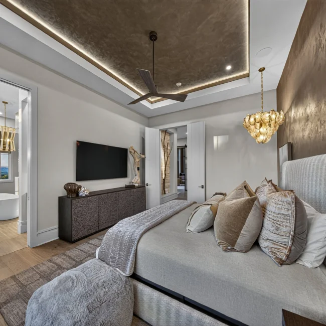 Primary bedroom with a gold leaf plaster ceiling and wall, a bed with a tall upholstered headboard and a bath view