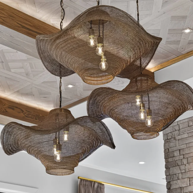 Three woven mesh pendant lights with ruffled edges hang below a white-washed parquet ceiling framed by wood beams