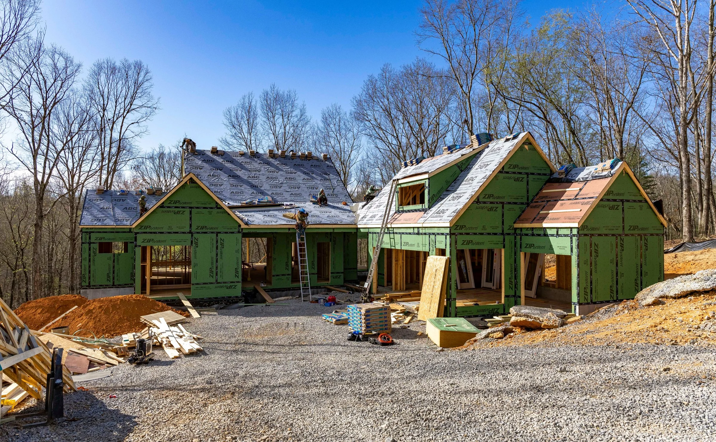 Framed two-story home with exposed sheathing and gravel drive on a wooded lot, by Mike Stevens Homes