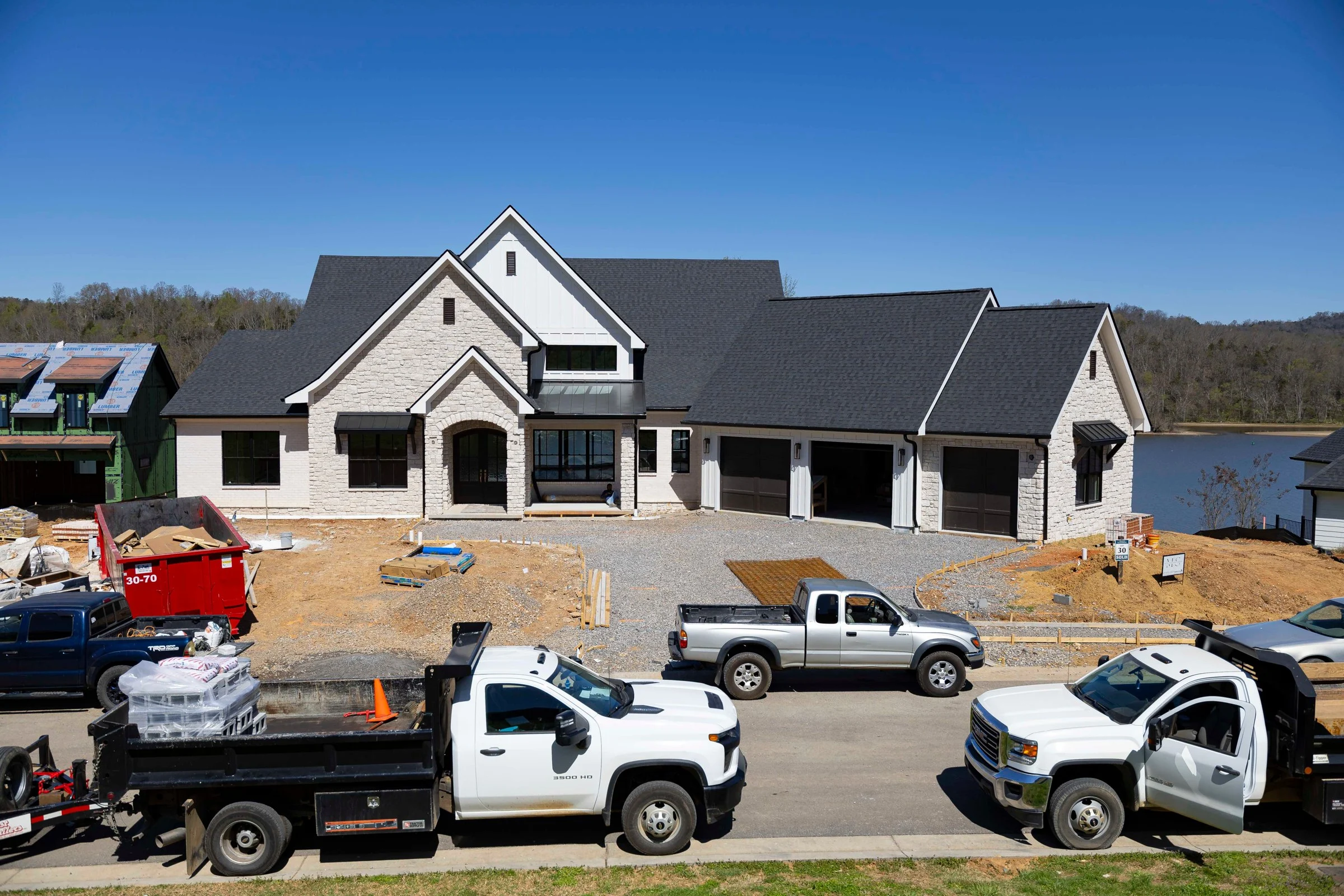 Newly framed luxury home with work trucks parked in the jobsite driveway, by Mike Stevens Homes