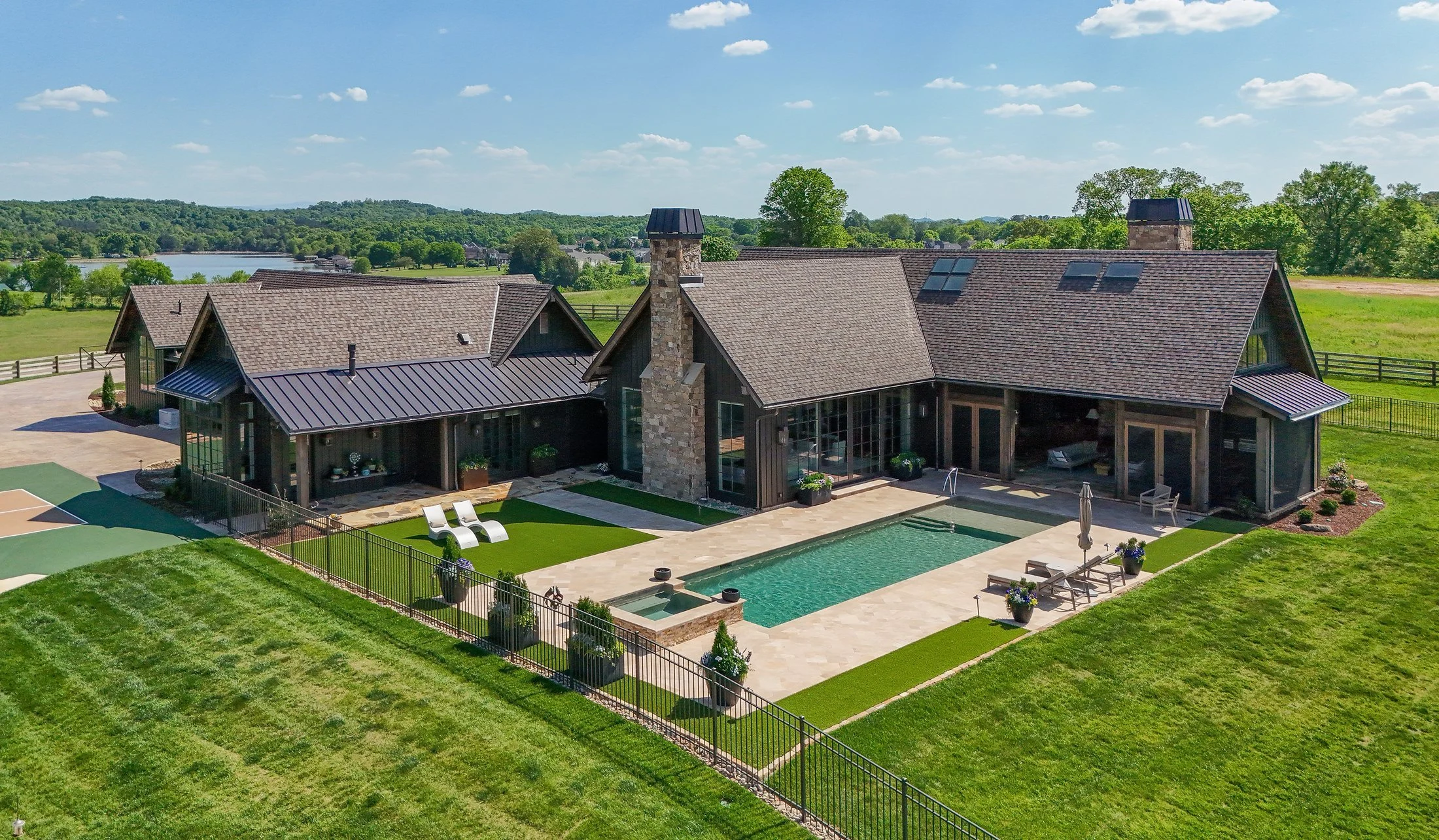 Aerial of stone-chimney lodge with pool and patio in Stillwater Lodge, a custom home by Mike Stevens Homes